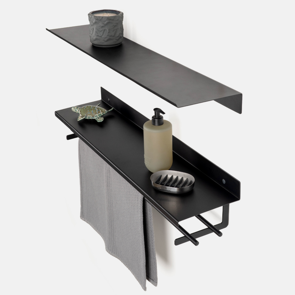 Black metal double wall-mounted shelf set with a towel bar, shown against a light gray wall with decorative bathroom items on the shelves.
