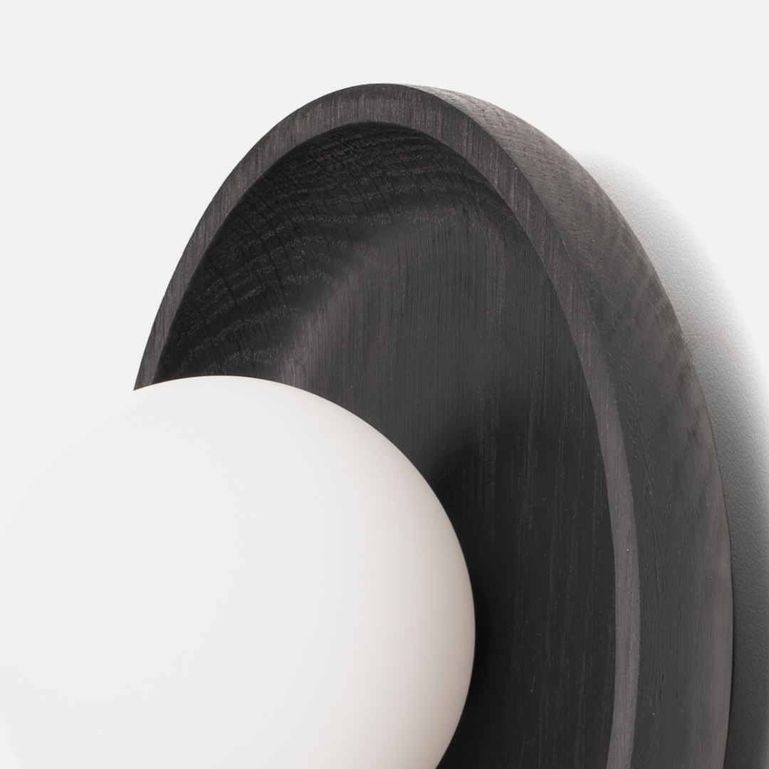 Wall-mounted light fixture with dark wooden finish and white bulb on a white background