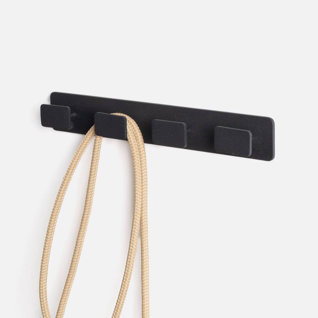 Black wall hook with a beige rope on a white background
