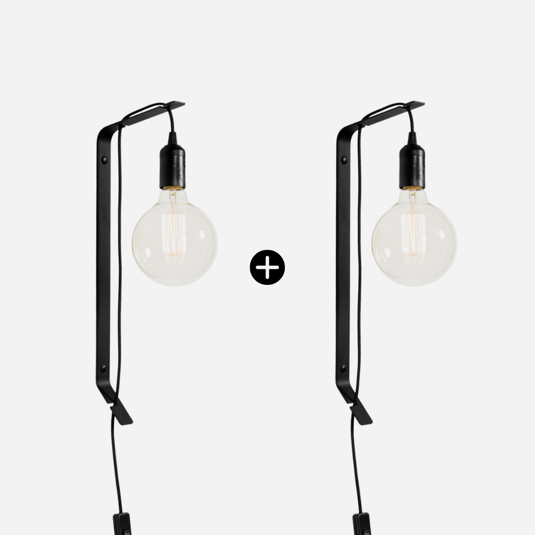 Two black wall-mounted lamps with exposed bulbs on a white background