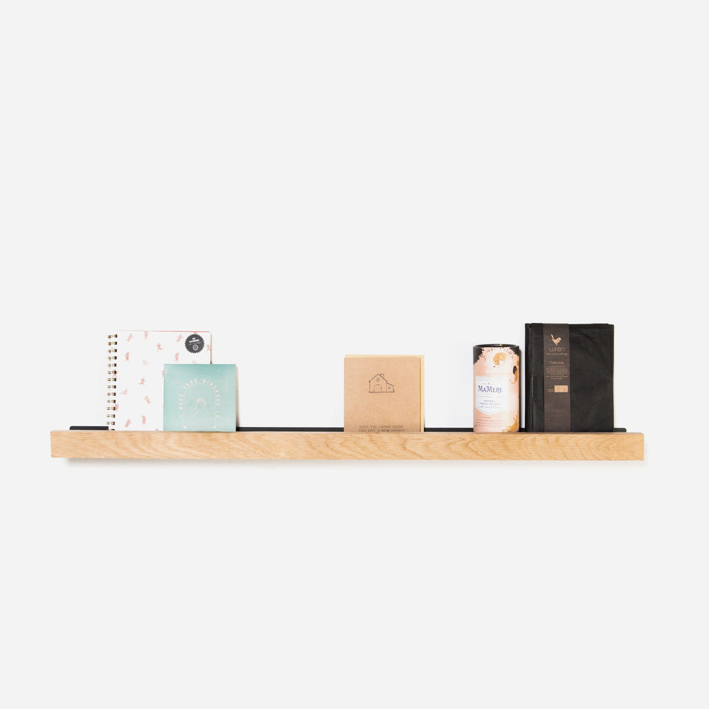 A natural oak lip shelf with various decorative items placed on it, against a white background.